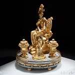Antiques 13 Elegant gilt bronze and marble inkwell, France 1810-15 The group rests on four corbels and is decorated at the base with a ribbon knotted with bows. A small gilt bronze openwork balustrade houses the vessels and the central sculpture, which depicts the goddess Athena.